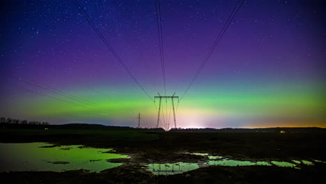 Time-lapse-of-a-aurora-polaris-and-clouds-moving-over-electric-wires-on-a-wet-field