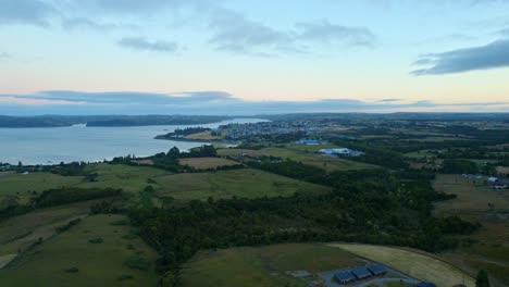 Aerial-Drone-Above-Chiloé-Chilean-Patagonian-Island-Landscape,-Chonchi-background,-environment,-nature-of-South-America,-blue-sea-bay-with-skyline-at-sunset