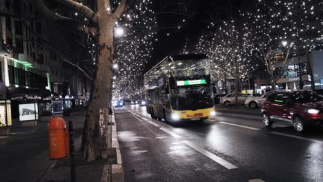 Christmas-lights-on-street-of-Kurfürsten-Damm-Berlin-Germany,-holiday-decorations,-cars-and-bus-driving-by