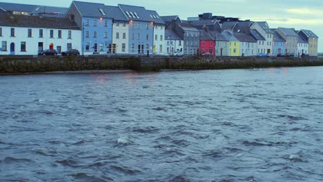 Tilt-shot:-Corrib-River-current-to-colorful-Long-Walk-houses,-Galway,-early-morning