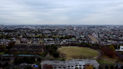 Eine-Weitläufige-Stadtlandschaft-Mit-Gebäuden-Und-Einem-Zentralen-Park,-Bewölkter-Himmel,-Luftaufnahme