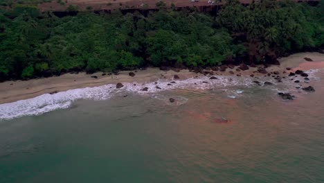 Aerial-drone-view-Drone-is-moving-towards-the-camera-where-there-are-lots-of-trees-and-a-couple-doing-a-pre-wedding-shoot-and-the-water-waves-are-reaching-the-shore