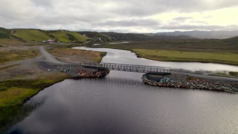 Drone-Sobrevolando-Un-Pequeño-Puente-Sobre-El-Río-Con-Un-Impresionante-Paisaje-Natural-En-El-Fondo,-Cucao