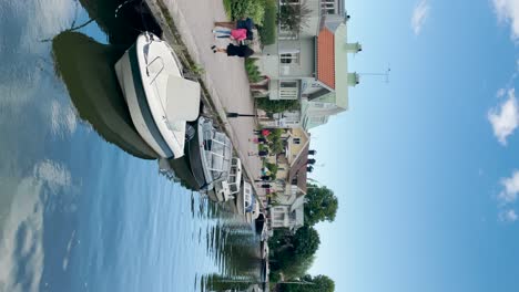 Menschen-Laufen-Mit-Booten-Auf-Dem-Fluss-In-Der-Stadt-Trosa-In-Schweden,-Vertikal
