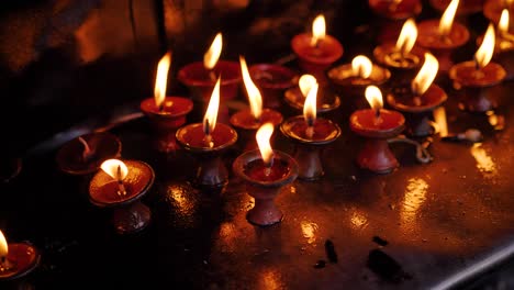 Close-view-of-butter-lamps-at-sunrise-at-the-Monkey-Temple,-Kathmandu,-Nepal