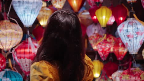 Woman-in-yellow-Ao-Dai-admiring-colorful-lanterns-in-Hoi-An-at-dusk,-vibrant-cultural-scene