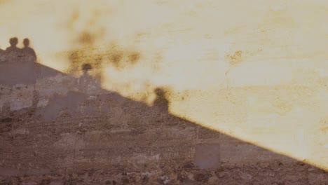 Shadow-on-orange-ancien-wall-of-four-peoples-walkings-and-leaf