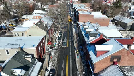 Driving-american-yellow-school-bus-on-road-in-american-town-at-winter-snow