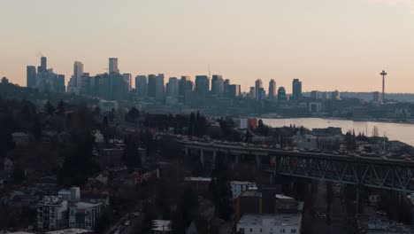 Traffic-flows-across-a-bridge-in-the-evening-golden-hour-with-the-downtown-Seattle-skyline-and-Space-Needle-by-Lake-Union-in-the-background