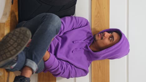 Vertical-shot-of-man-wearing-purple-hoodie-talks-to-someone-sitting-on-bench