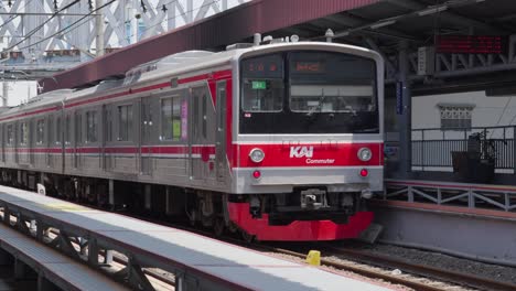 El-Tren-Plateado-Sale-De-La-Estación-En-Banten,-Transporte-Público-Indonesio,-La-Gente-Camina-Por-El-Ferrocarril-Del-Sudeste-Asiático.