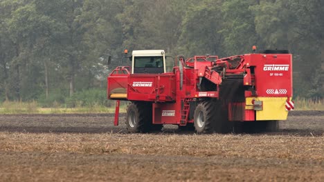 Slow-following-pan-of-heavy-machinery-crop-harvester-in-farmland-soil-collecting