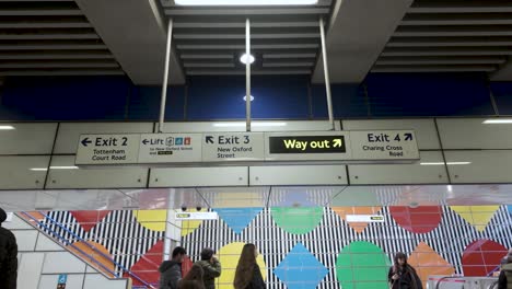 Blick-Auf-Die-Hängenden-Ausgangsschilder-An-Der-Tottenham-Court-Road-Station,-Während-Pendler-Vorbeigehen