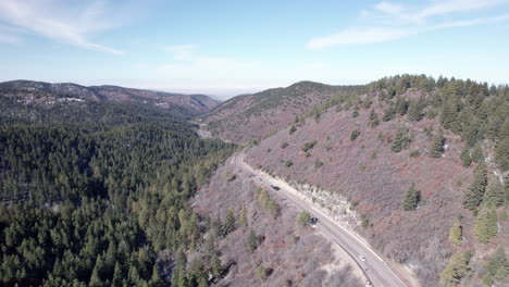 Los-Coches-Circulan-Por-Una-Carretera-En-Una-Montaña-Rodeada-De-Bosques-De-Pinos,-Drones-Aéreos