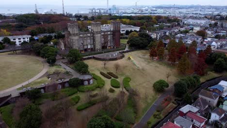 A-historical-castle-with-autumn-trees-in-a-suburban-setting,-overcast-sky,-aerial-view