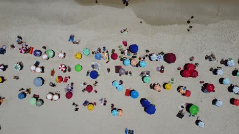 Drohne-Mit-Kamera-90-Grad-Nach-Unten-Mit-Seitlicher-Bewegung-Filmt-Mehrere-Bunte-Sonnenschirme-Und-Menschen-Am-Strand-Von-Ipanema,-Brasilien