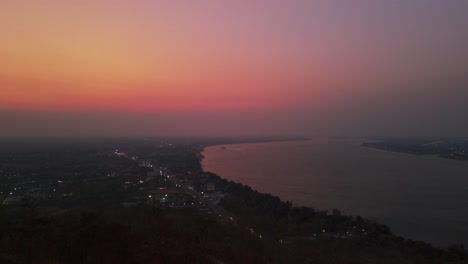 Golden-Beleuchteter-Buddha-Mit-Blick-Auf-Den-Mekong,-Lebendigen-Sonnenuntergang,-Pakse,-Laos