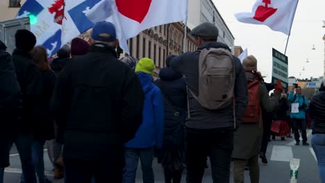 Covid-regulation-protest-march-with-flags-in-Sweden,-seen-from-behind