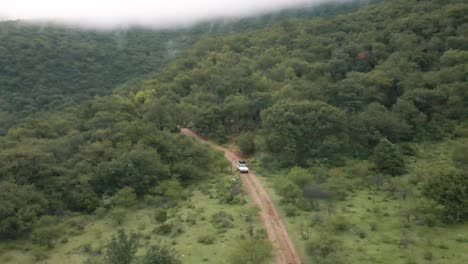 Weißer-Cherokee-Truck-Fährt-Bei-Nebligem-Bergwetter-Durch-Den-Wald,-Drohnenaufnahme-Aus-Der-Luft