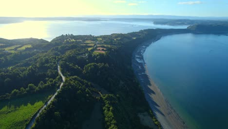 Isla-Patagónica-De-Chiloé-Panorámica-Aérea-Del-Canal-De-Agua-De-La-Unión-De-Drones,-Isla-Lemuy-Y-Paisaje-Detif,-Islotes-Verdes-Con-Amanecer-Reflejado