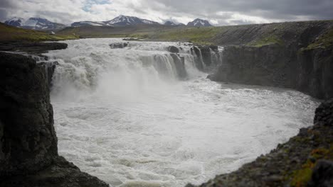 Statische-Aufnahme-Von-Herrlichen,-Epischen-Wasserfällen-Und-Einem-Fluss-Mit-Schneebedeckten-Bergen-Im-Hintergrund