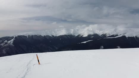 Snow-capped-Iezerul-Mare-Peak-under-a-cloudy-sky-in-Iezer-Papusa-Mountains,-Romania,-wide-shot