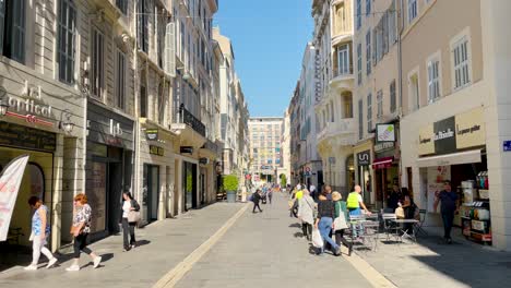 People-walk-by-restaurant-on-pedestrian-street-in-sunny-Marseille