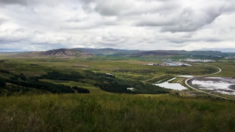 Expansive-view-of-Icelandic-landscape-with-mountains-and-cloudy-skies,-greenery-in-the-foreground