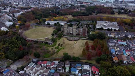 Ein-Weitläufiges-Vorstadtgebiet-Mit-Häusern,-Einem-Schloss-Und-Grünflächen-In-Der-Abenddämmerung,-Luftaufnahme