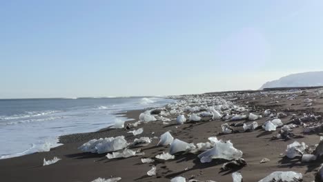 Un-Dron-De-4k-Captura-Imágenes-Aéreas-Cinematográficas-De-Olas-Rompiendo-Que-Llegan-A-La-Costa,-Con-Hielo-Roto-De-Los-Glaciares-Dispersos-En-El-Suelo