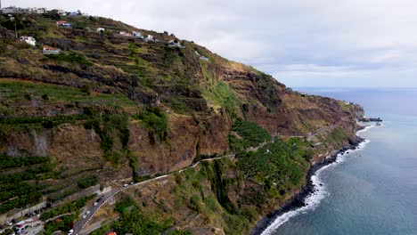 Hover-above-the-coastal-highways-of-Madeira,-where-the-road-hugs-the-shoreline,-providing-travelers-with-breathtaking-ocean-views-at-every-twist-and-turn