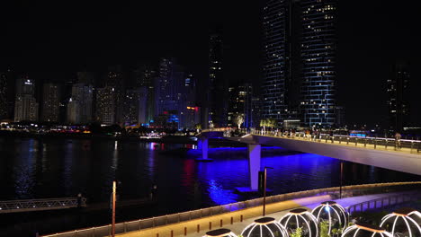 Dubai-UAE-Waterfront-Skyscrapers-and-Bluewaters-Bridge-at-Night,-Futuristic-Cityscape