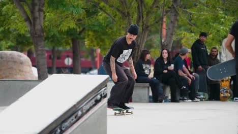 Un-Adolescente-Vestido-De-Negro-Presumiendo-Ante-Sus-Amigos-Hace-Un-Aniquilamiento-En-Su-Patineta-Haciendo-Un-Truco-En-Un-Parque-De-Patinaje