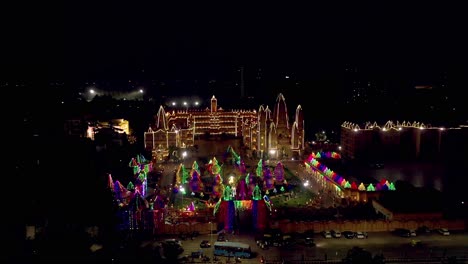 Vista-Aérea-De-Drones-Con-Cámara-De-Drones,-El-Templo-Se-Ve-Muy-Hermoso-Con-Luces-Y-Muchas-Personas-Observan-La-Iluminación-Desde-Afuera