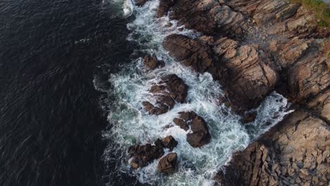 Aerial-top-down-Atlantic-Ocean-waves-crashing-in-to-rocky-coastline-drone-revealing-Ogunquit-Maine-USA-during-golden-hours