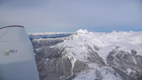 Blick-Auf-Die-Tragfläche-Eines-Flugzeugs,-Das-über-Bergiges,-Schneebedecktes-Gelände-Fliegt