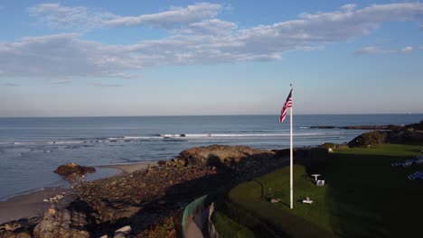 Ogunquit,-Maine,-USA---Drohnenflug-In-Der-Nähe-Der-US-Flagge,-Der-An-Sonnigen-Tagen-Eine-Malerische-Meeresküste-Zeigt