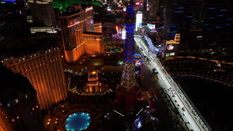 Eiffel-Tower-replica,-lit-in-colors-of-France,-night-in-Las-Vegas---Aerial-view