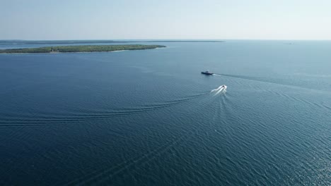 Drohnenaufnahme-Eines-Bootes,-Das-An-Einem-Sonnigen-Tag-An-Einer-Fähre-Vorbeifährt,-Die-Auf-Dem-Weg-Zum-Meer-Ist