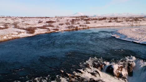 Salmon-fishing-river-with-Arbaejarfoss-Waterfall-during-snowy-winter-at-sunset