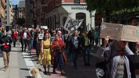 Women-with-dog-march-at-climate-protest-rally,-Act-Now-sign,-slo-mo