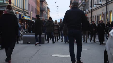 Warmly-dressed-people-walk-on-street-in-Stockholm,-static-slomo