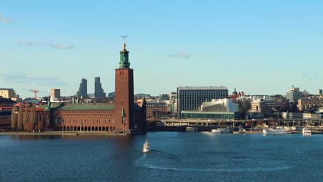 Breite-Statische-Sicht-Auf-Die-Fähre-Auf-Dem-Wasser-Durch-Das-Stockholmer-Rathaus-Und-Die-Skyline