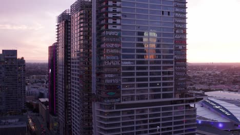 Rising-reverse-pullback-aerial-shot-of-the-abandoned-Oceanwide-Plaza-high-rise-towers-covered-in-colorful-graffiti-murals-at-sunset-in-downtown-Los-Angeles,-California