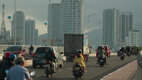 Vietnamese-People-Riding-Motorcycles-and-Driving-Cars-on-Xom-Bong-Bridge-in-Nha-Trang-City,-Skyscraper-Buildings-in-Background,-Vietnam