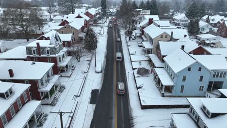 Luftaufnahme-Des-Verkehrs-Auf-Der-Hauptstraße-In-Einem-Verschneiten-Amerikanischen-Wohngebiet-Aus-Der-Vogelperspektive