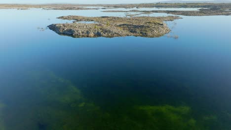 Afiladas-Rocas-De-Piedra-Caliza-Sobresalen-De-Las-Aguas-Inundadas-De-Musgo-En-El-Burren-Irlanda,-Plataforma-Rodante-Aérea-En-Un-Día-Soleado