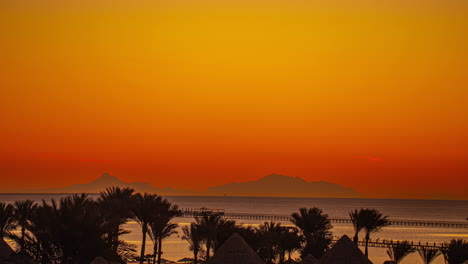 Zeitraffer-Des-Sonnenaufgangs,-Der-Den-Himmel-Am-Strand-Mit-Palmen-Und-Einem-Boot-Im-Hintergrund-Erhellt