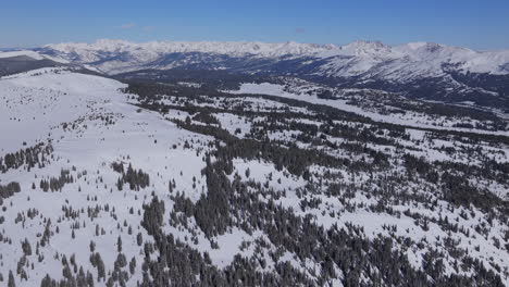 Invierno-Paso-De-Vail-Colorado-Drone-Aéreo-I70-Montañas-Rocosas-Paisaje-Colina-De-Perdiz-Pico-Indio-Mañana-Soleada-Cielo-Azul-Polvo-Profundo-Snowboard-Esquiador-Moto-De-Nieve-Travesía-Adelante-Panorámica-Hacia-Arriba-Revelar