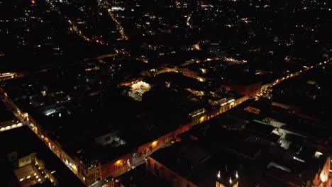 Bird's-eye-view-over-Jardin-Allende,-Quiosco-Picorete,-El-Campanario-and-Parroquia-de-San-Miguel-Arcangel-in-San-Miguel-de-Allende-at-night